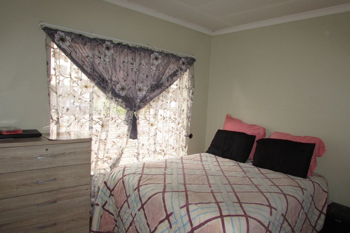 A functional bedroom featuring a window with natural light and neutral wall finishes.