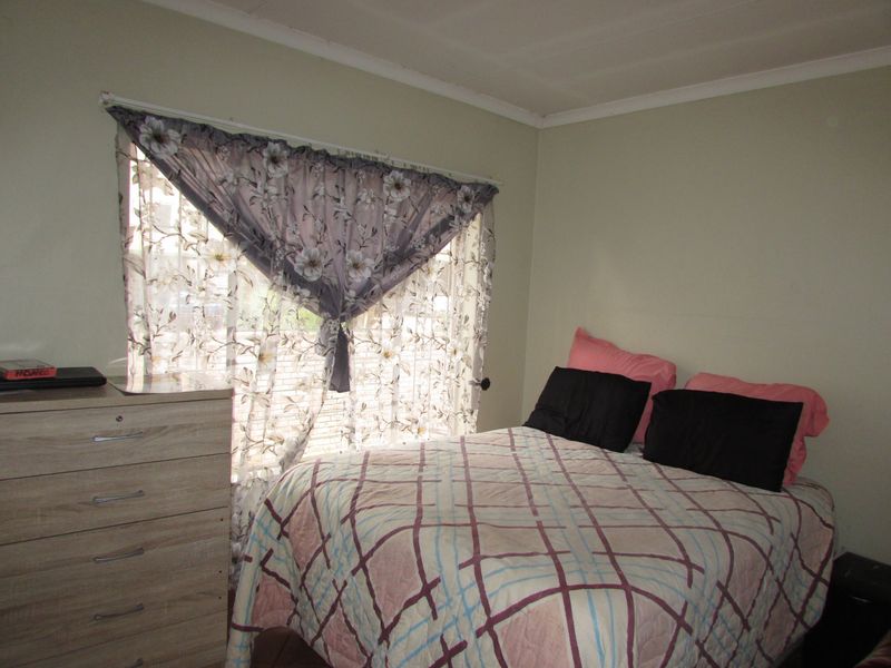 A functional bedroom featuring a window with natural light and neutral wall finishes.