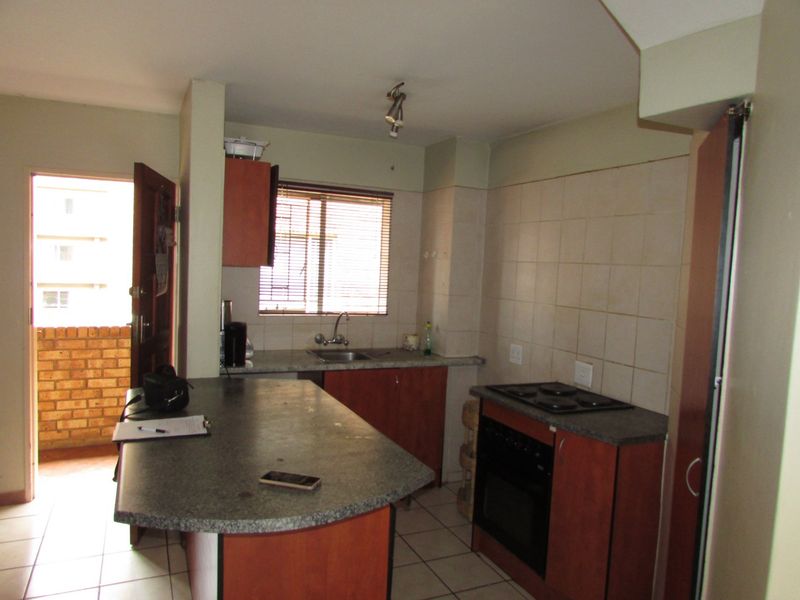Functional kitchen featuring a breakfast bar, built-in oven and hob, tiled flooring, and direct access to an outdoor balcony area.