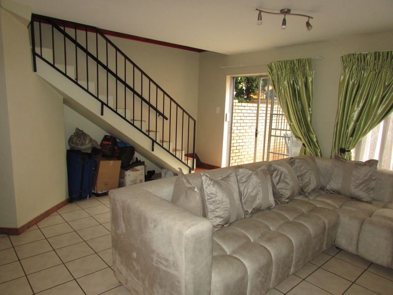 Open plan living area featuring tiled flooring, a staircase with metal balustrade, and sliding glass doors leading to an outdoor space.