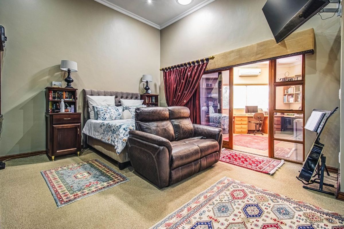 Spacious bedroom featuring high ceilings, carpeted flooring, and large sliding glass doors providing access to an adjoining office space.
