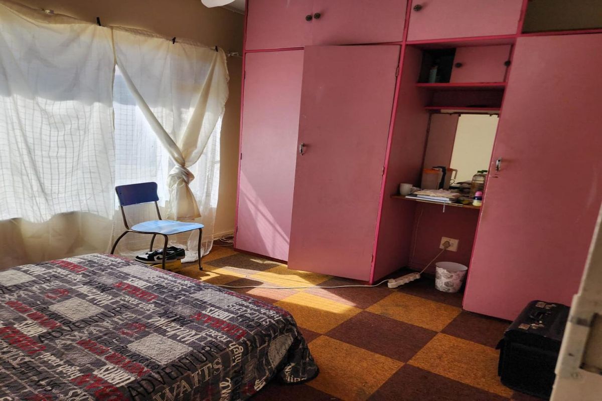 A bedroom featuring built-in pink cabinetry with an integrated vanity area and checkered floor tiles.