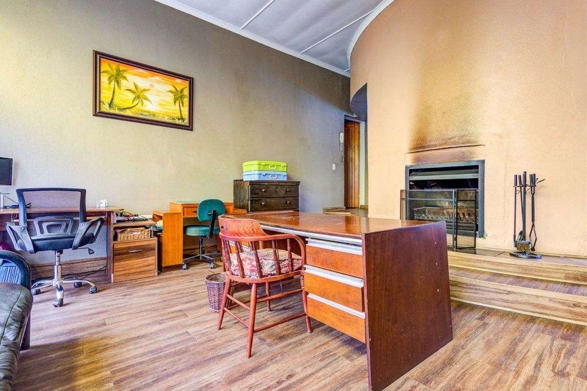 A home office or living space featuring a built-in fireplace with a raised hearth and wood-look flooring.