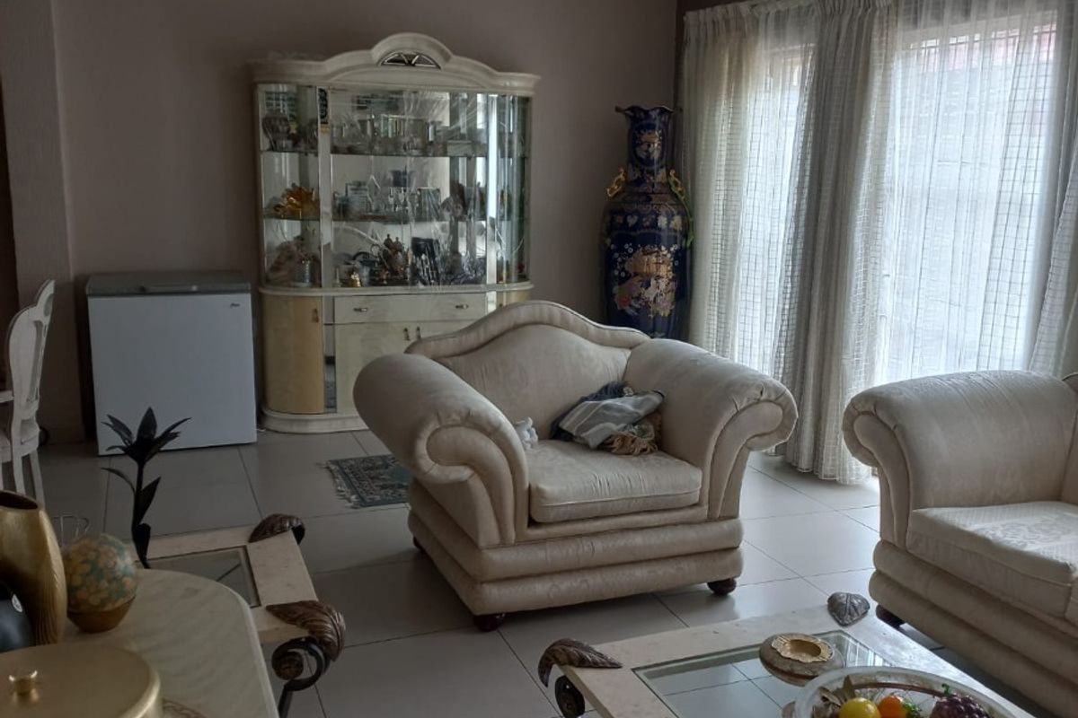 A spacious living room featuring neutral tiled flooring and large sliding glass doors that provide natural light.