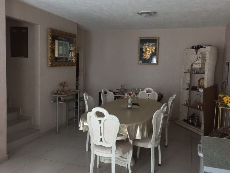 A dining room featuring tiled flooring and a textured ceiling, with an adjacent staircase leading to another level.