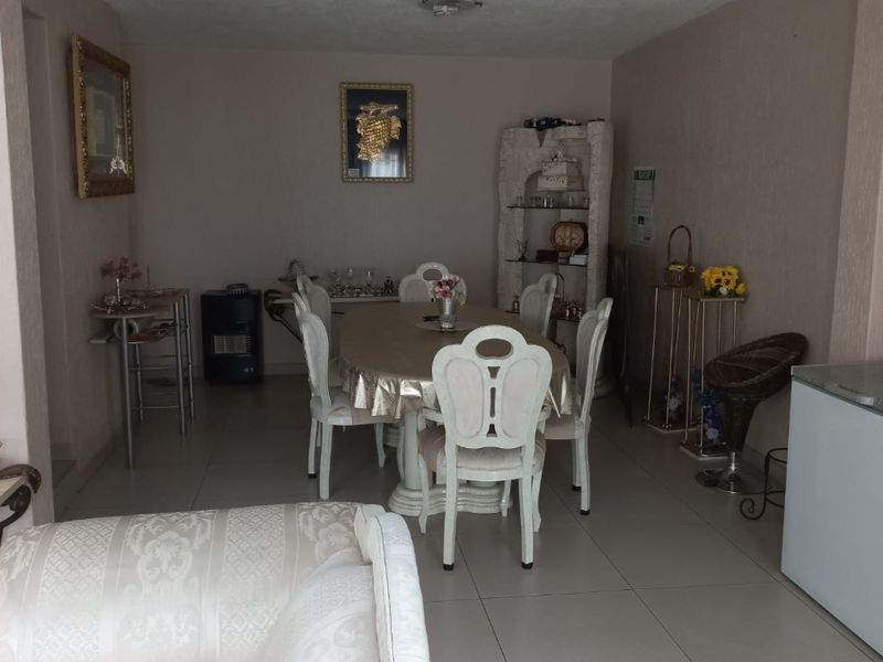 Open plan living and dining area featuring neutral wall tones and tiled flooring, providing a functional space for daily living and entertaining.