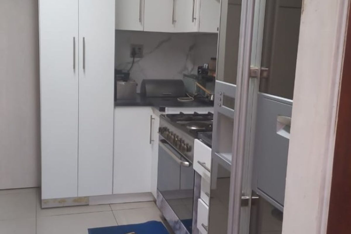 A compact, modern kitchen featuring white cabinetry, stone countertops, and a built-in gas stove with oven, finished with neutral floor tiles.