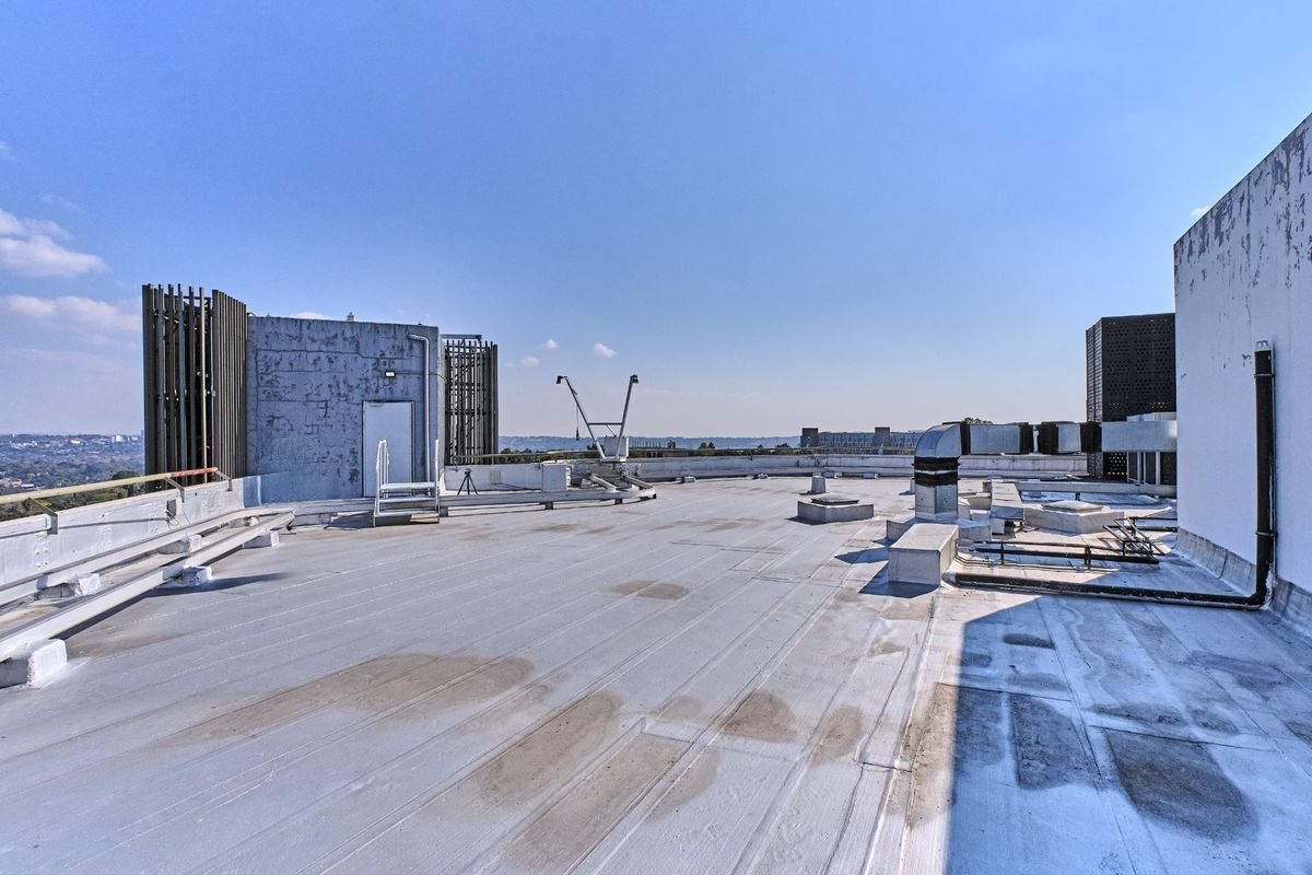 Expansive commercial rooftop area featuring exposed HVAC ducting, ventilation infrastructure, and panoramic views, suitable for utility or potential rooftop development.