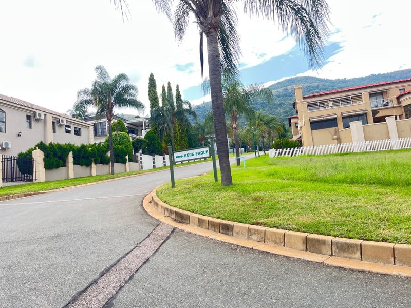 A view of the residential street within the estate, featuring paved roads, manicured lawns, and surrounding residential properties with mountain views.
