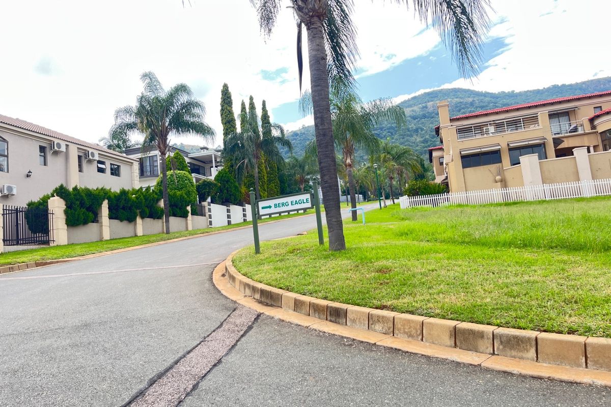 A view of the residential street within the estate, featuring paved roads, manicured lawns, and surrounding residential properties with mountain views.