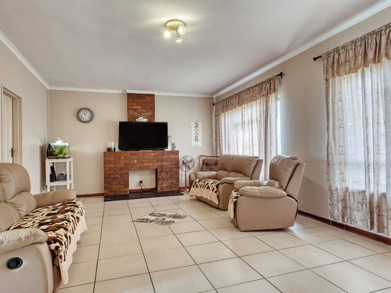 Spacious living room featuring a central brick fireplace, neutral wall tones, and ceramic tile flooring throughout.
