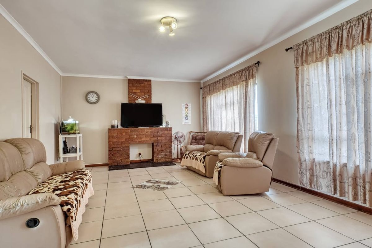Spacious living room featuring a central brick fireplace, neutral wall tones, and ceramic tile flooring throughout.