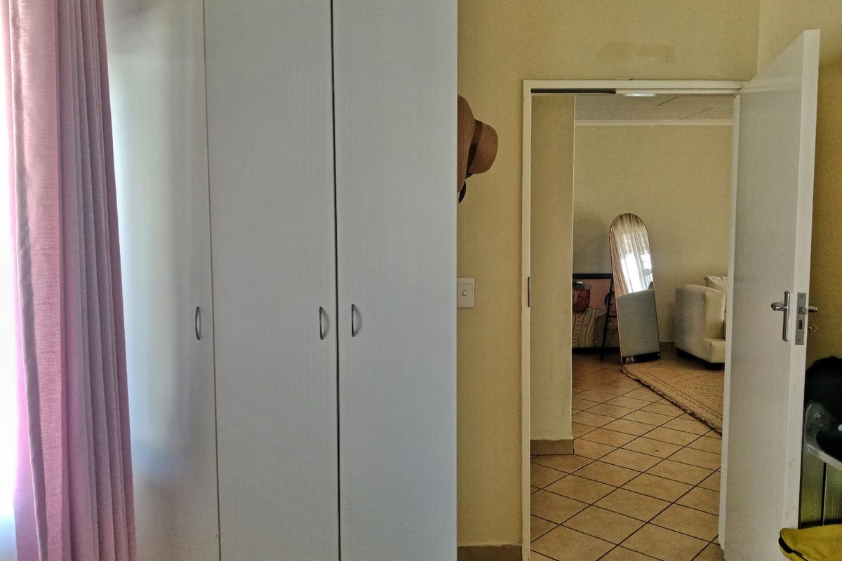Bedroom interior featuring built-in white cabinetry and a doorway leading to an adjacent tiled living area.