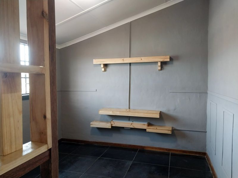 An interior room featuring dark tiled flooring, grey painted walls, and custom-fitted wooden shelving units.