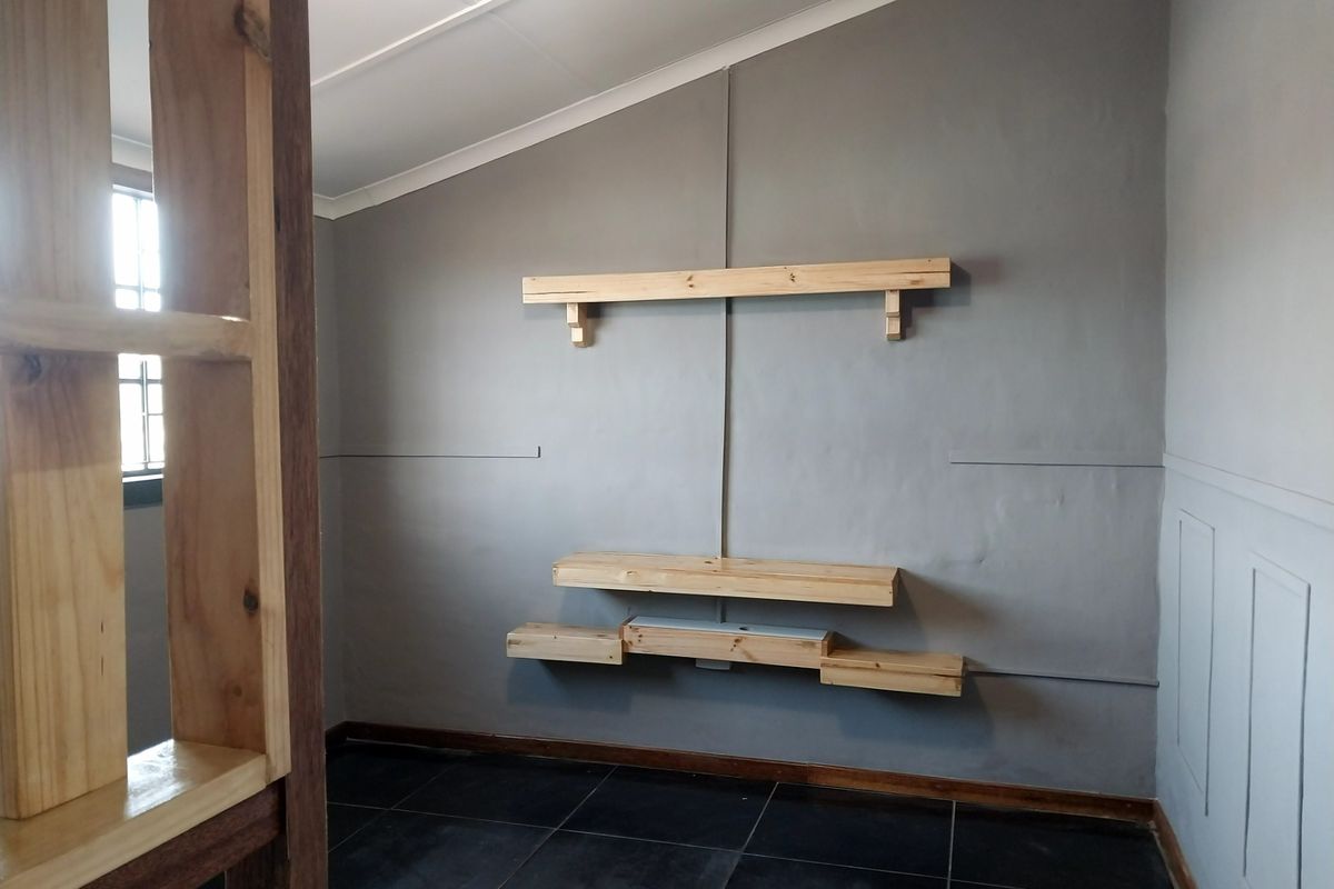An interior room featuring dark tiled flooring, grey painted walls, and custom-fitted wooden shelving units.