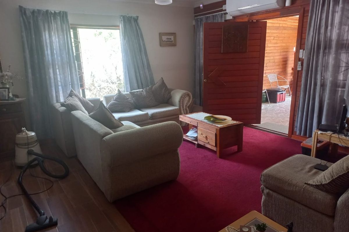 A living room featuring a split-system air conditioner, ceiling fan, and a mix of tiled and carpeted flooring with direct access to an outdoor area.