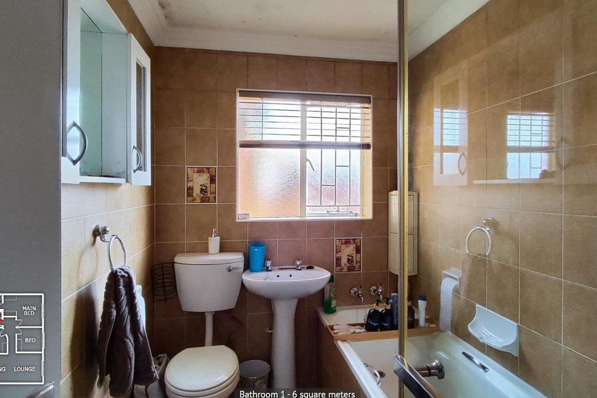 A compact bathroom featuring a pedestal basin, toilet, and a shower-over-bath combination with full-height wall tiling.
