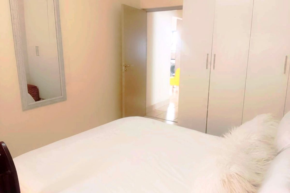 A bedroom featuring built-in floor-to-ceiling wardrobes and a doorway leading to an adjacent room.