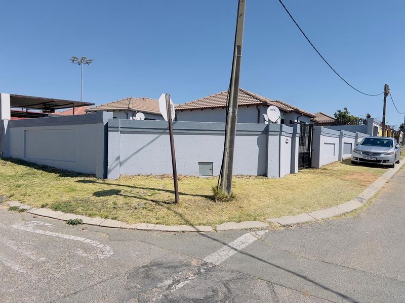 Street view of the property featuring a secure perimeter wall, tiled roof, and gated entrance.