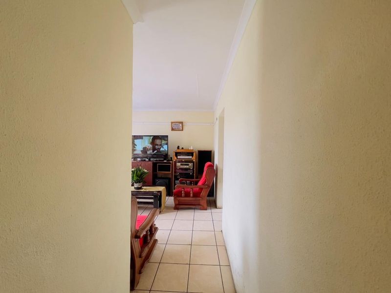 A view from a hallway looking into a living room area featuring tiled flooring and neutral wall finishes.