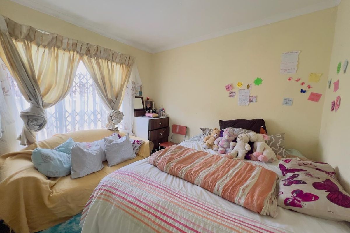 A bedroom featuring a window with security gate, coved ceiling, and neutral wall finishes.