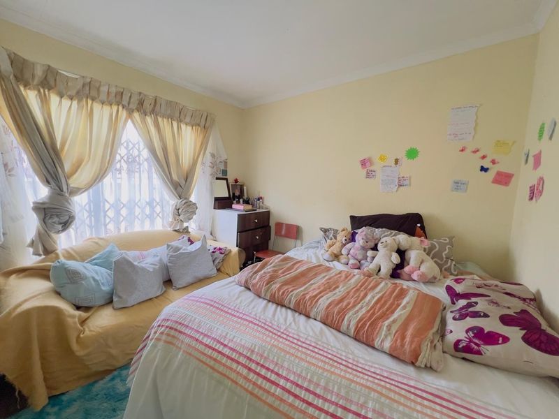 A bedroom featuring a window with security gate, coved ceiling, and neutral wall finishes.