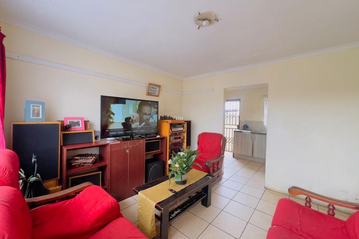 A functional living room featuring tiled flooring and a direct transition into the adjacent kitchen area.