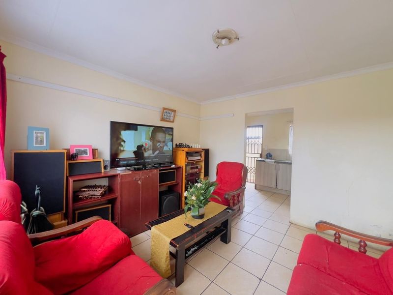 A functional living room featuring tiled flooring and a direct transition into the adjacent kitchen area.