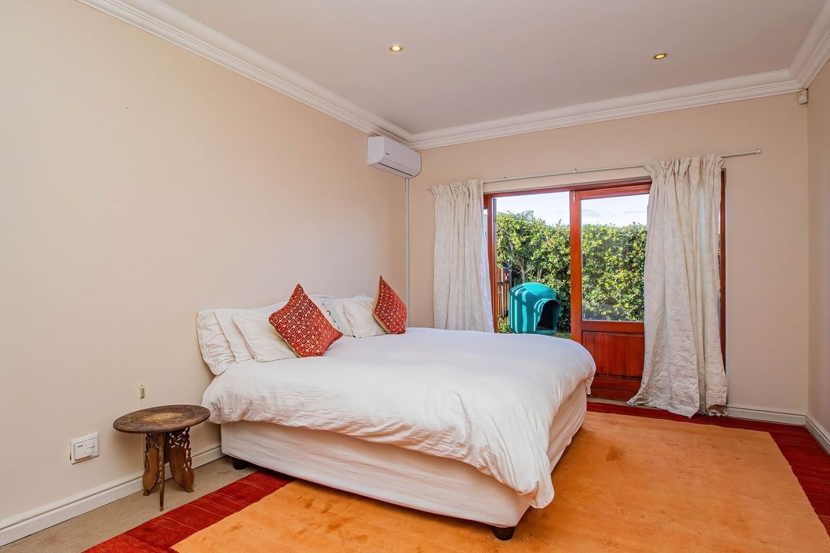A bedroom featuring crown molding, a wall-mounted air conditioning unit, and double doors providing direct access to the garden.