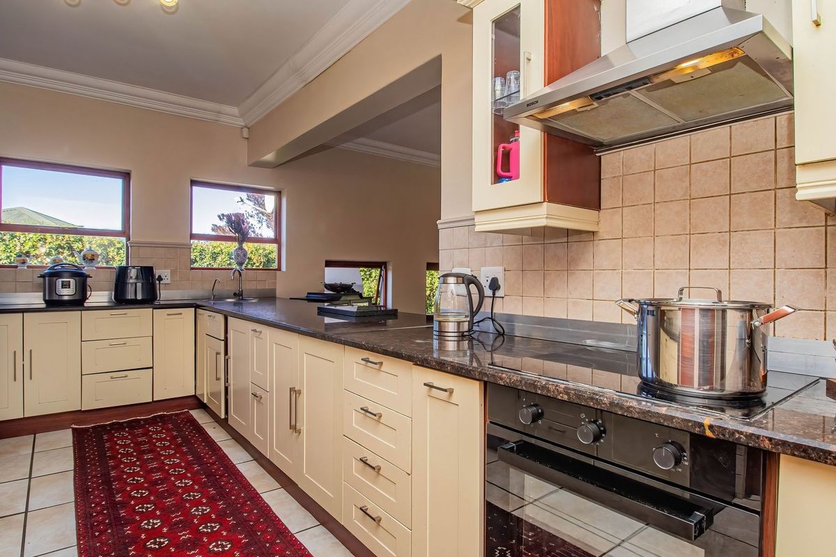 A functional kitchen featuring granite countertops, built-in oven, extractor fan, and tiled flooring with ample cabinetry for storage.