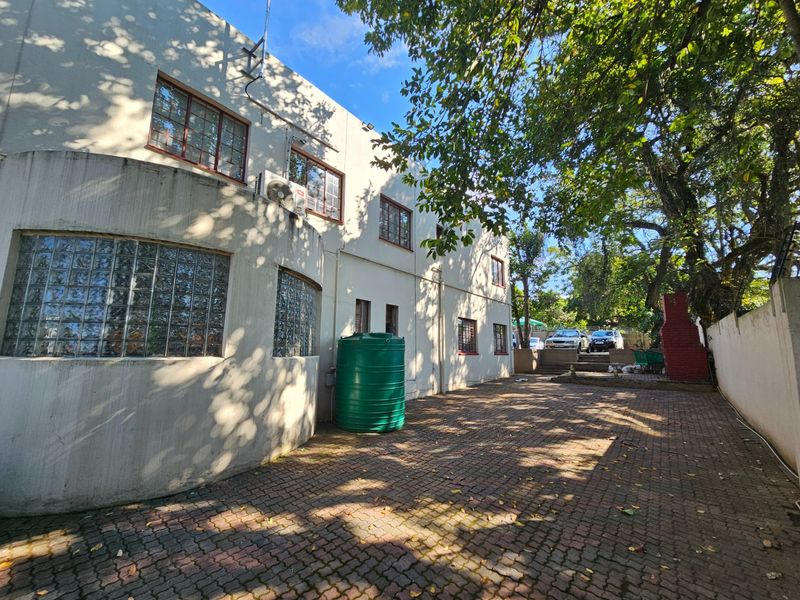Rear exterior view of the office building featuring paved courtyard, glass block windows, and a water storage tank.