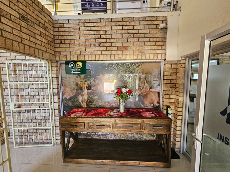 Office entrance area featuring exposed brickwork, tiled flooring, and a security gate, providing a professional and welcoming reception space.