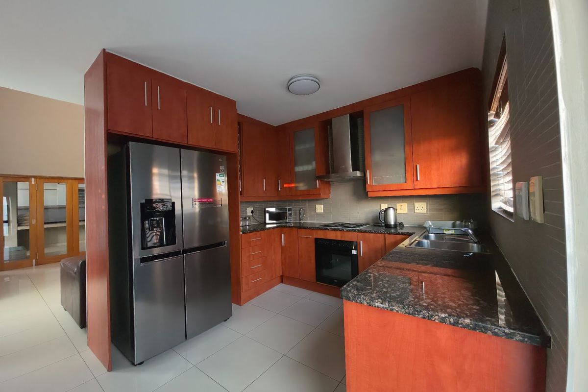 A functional kitchen featuring warm-toned wooden cabinetry, granite countertops, stainless steel appliances, and tiled flooring, offering a practical and well-maintained workspace.