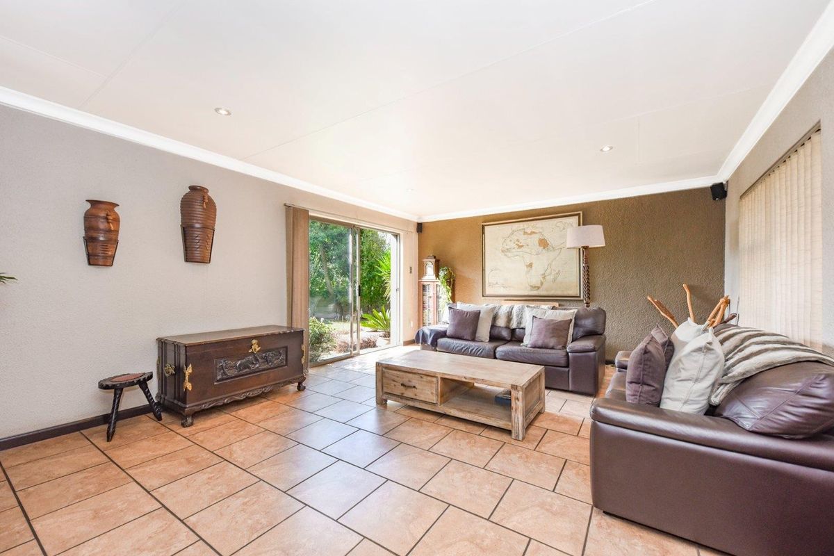 Spacious living room featuring tiled flooring, recessed downlighting, and a sliding glass door providing direct access to the garden area.