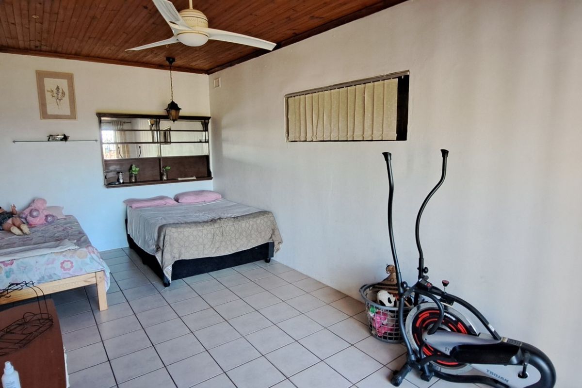 Spacious bedroom featuring tiled flooring, a timber-paneled ceiling with a fan, and a built-in wall mirror unit.