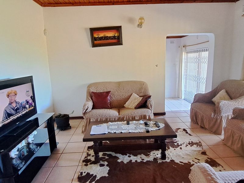 A living room featuring tiled flooring and a timber ceiling, with access to an outdoor area through a security-gated sliding door.