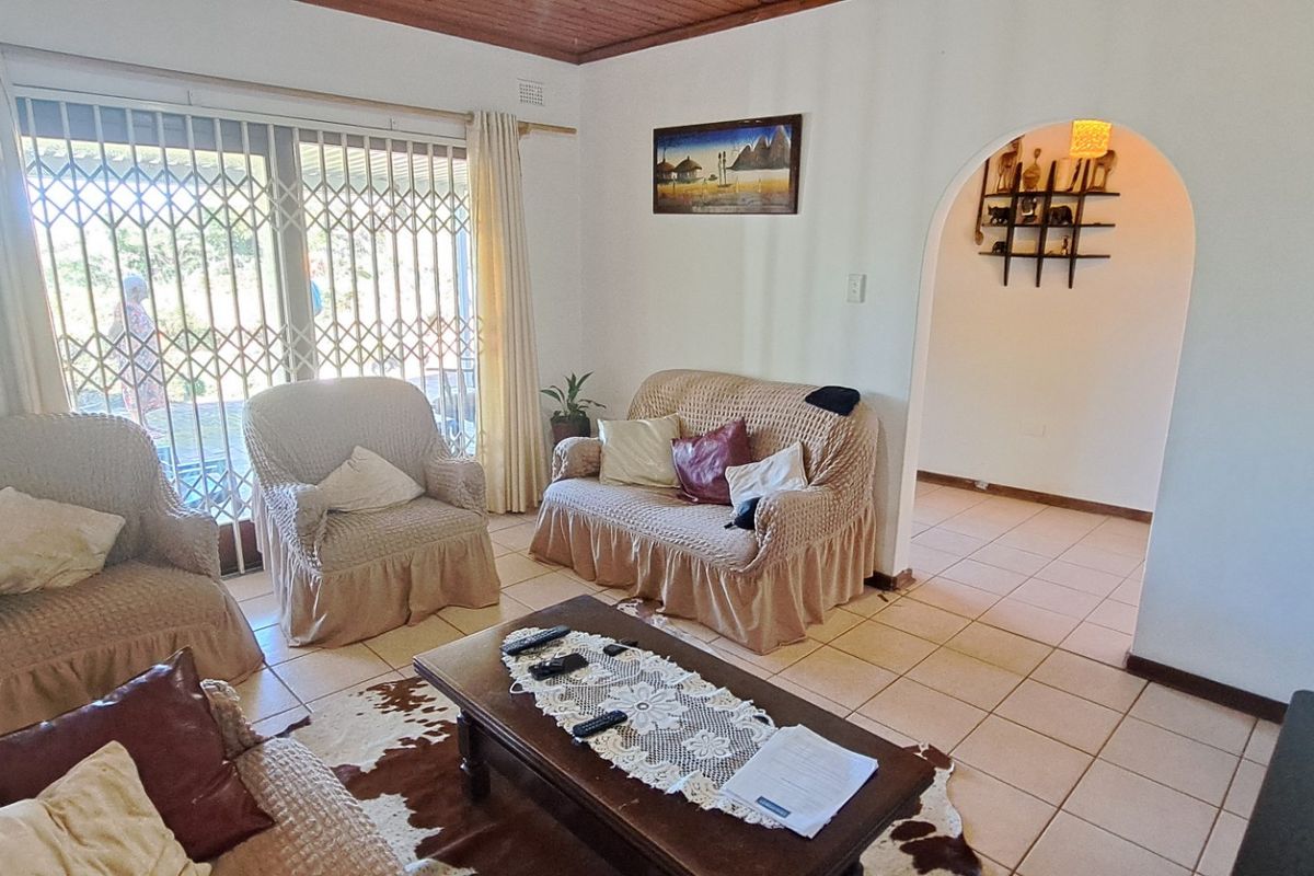 A living room featuring tiled flooring, a timber ceiling, and a sliding glass door with a security gate leading to the exterior.