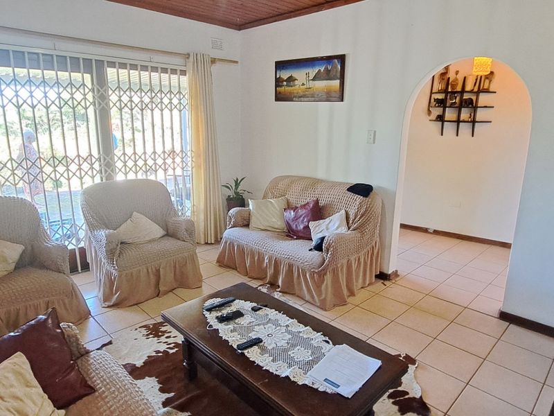 A living room featuring tiled flooring, a timber ceiling, and a sliding glass door with a security gate leading to the exterior.