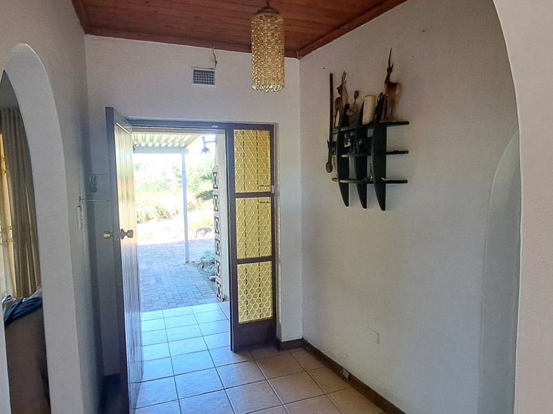 An entry hall featuring tiled flooring, a timber ceiling, and arched doorways leading to adjacent living spaces.