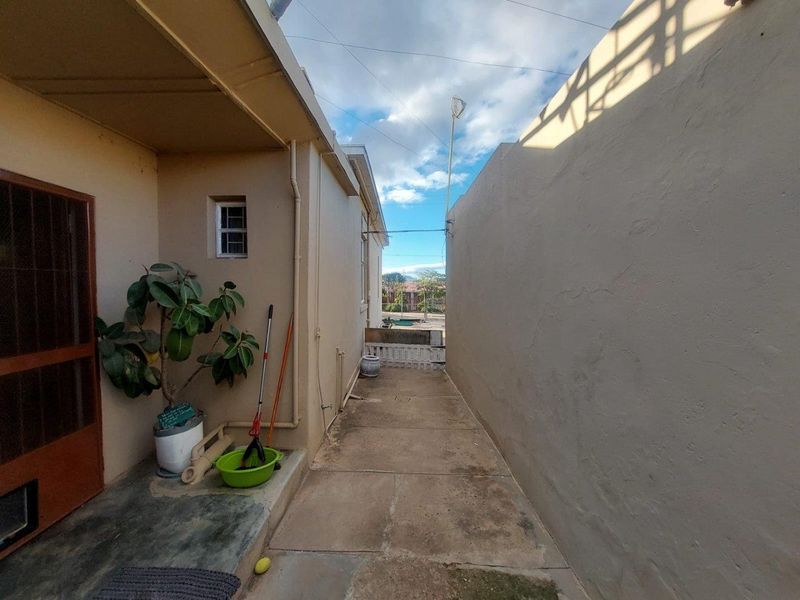 A narrow side passage or courtyard area featuring concrete paving and exterior wall access, providing a functional outdoor utility space.