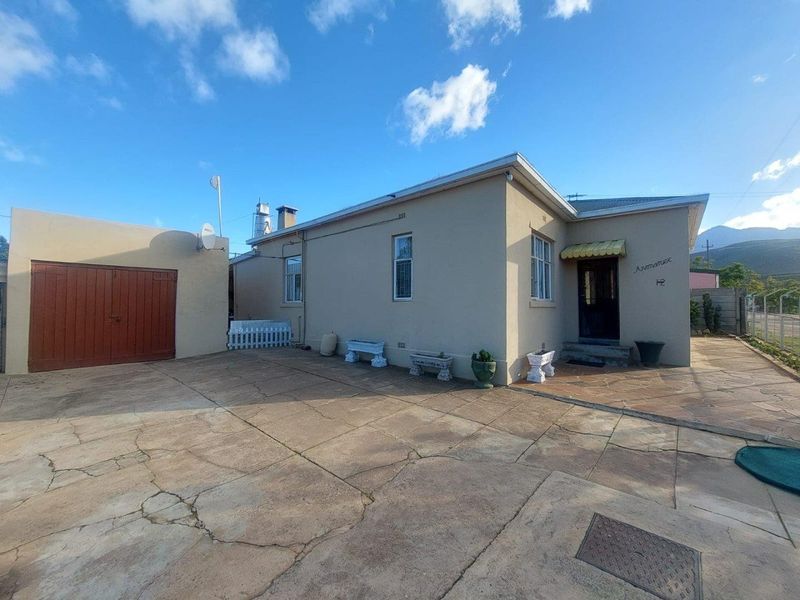 Exterior view of the property featuring a paved driveway, attached garage, and main entrance with a small awning.