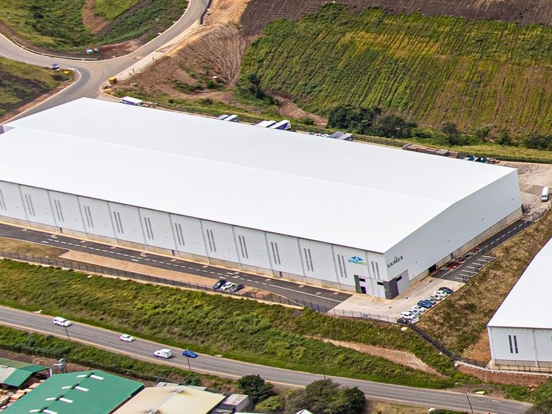 Aerial view of a large industrial warehouse facility featuring a modern metal roof, paved access areas, and secure perimeter fencing.
