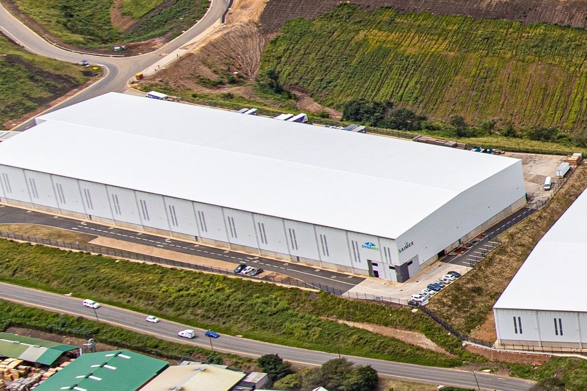 Aerial view of a large industrial warehouse facility featuring a modern metal roof, paved access areas, and secure perimeter fencing.
