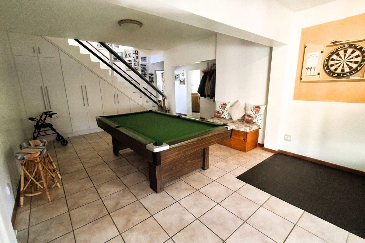 A versatile living area featuring tiled flooring and extensive built-in under-stair cabinetry, providing ample storage space within an open-plan layout.