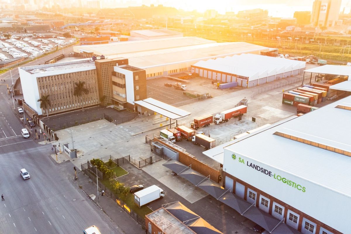Aerial view of a large industrial logistics facility featuring multiple warehouses, paved yard space, and secure perimeter fencing.