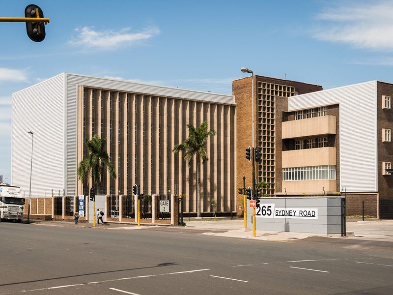 A street-level view of a large commercial office building located at 265 Sydney Road, featuring a prominent facade and secure gated entrance.
