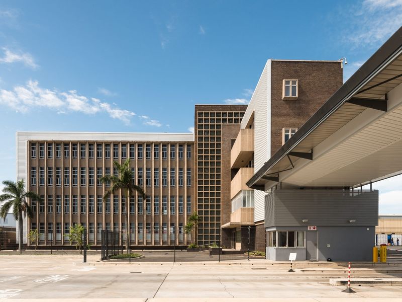 A professional exterior view of a multi-story office building featuring a modern security gatehouse and covered entrance walkway.