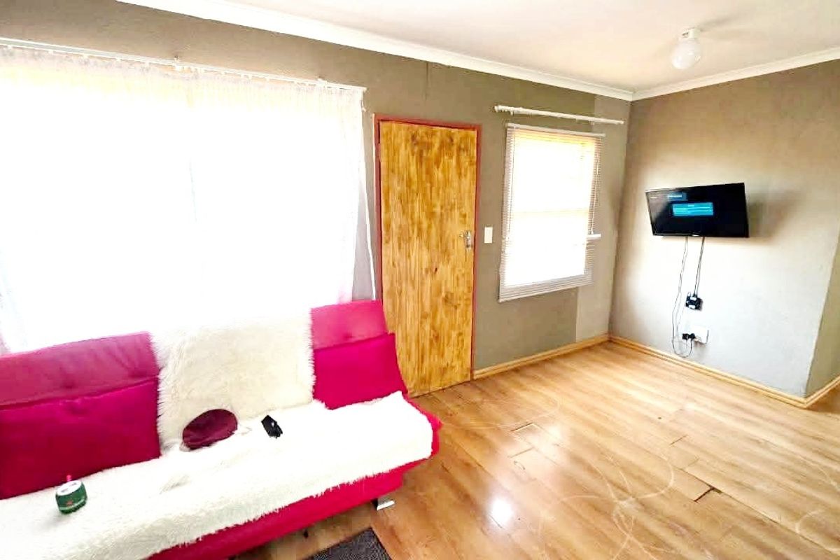 A living room featuring laminate flooring, natural light through windows, and a wall-mounted television point.