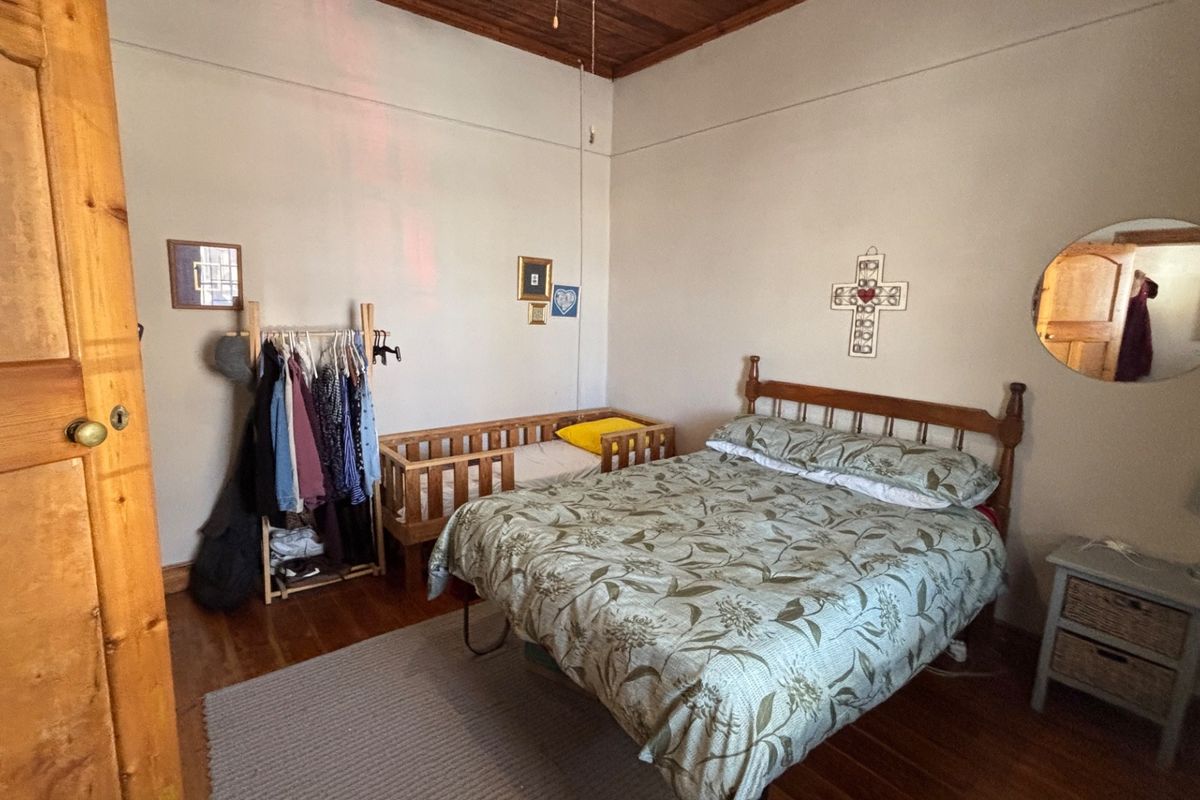 A bedroom featuring original timber ceiling beams and polished wooden flooring, providing a classic and warm atmosphere.