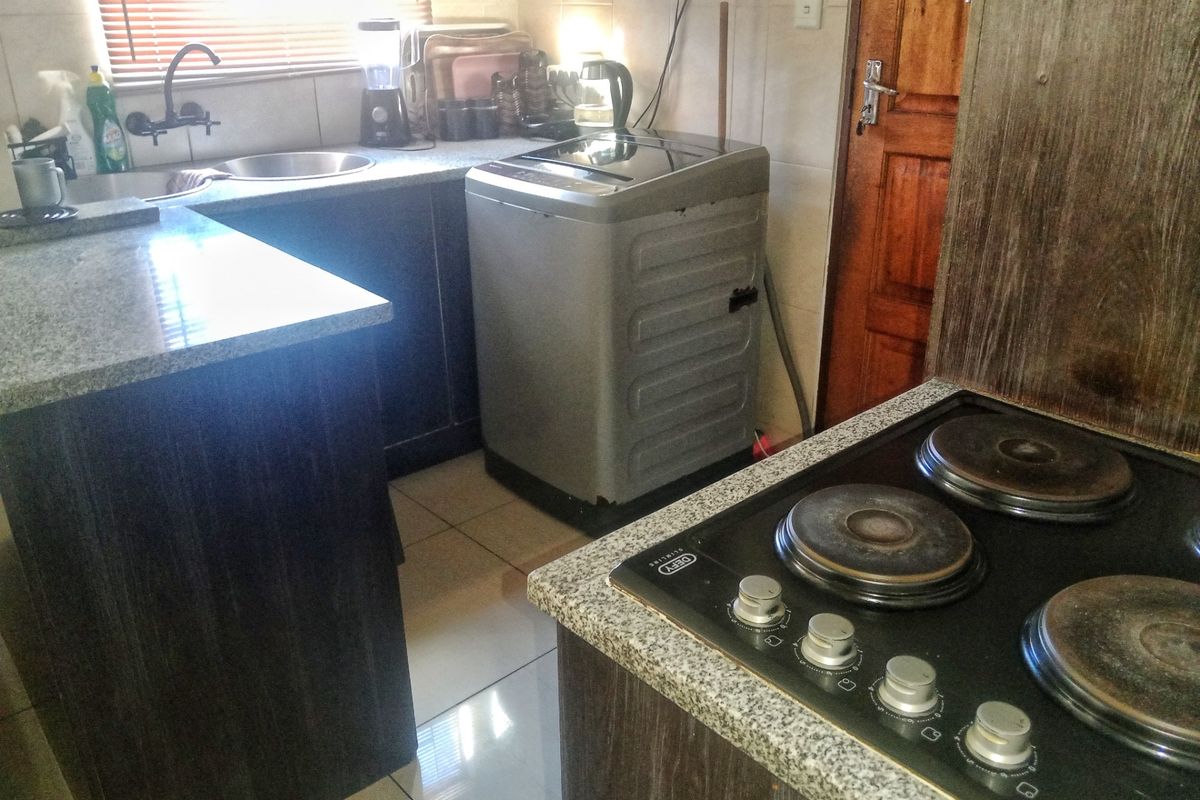 Compact kitchen featuring dark wood cabinetry, granite countertops, a built-in electric hob, and a stainless steel sink with a modern faucet.